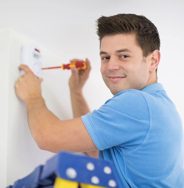 Installer mounting alarm system on wall looking at camera
