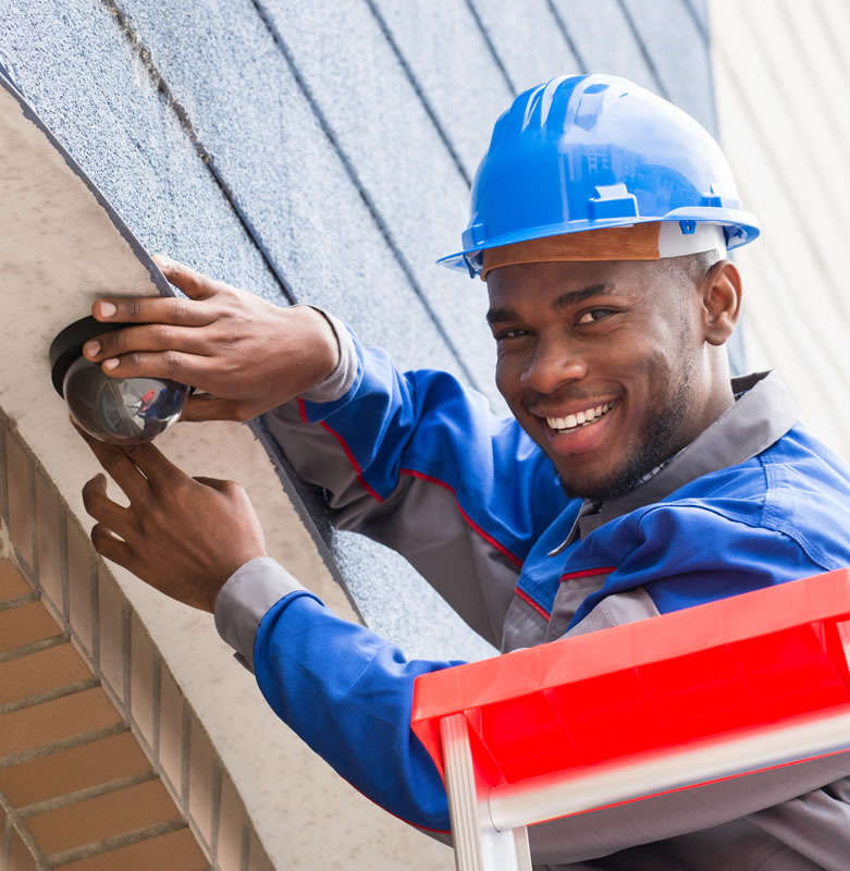 Installer fitting security alarm camera to building